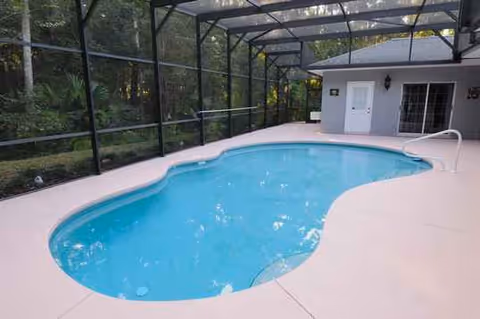 Covered outdoor pool area with a blue pool, white deck, and screened enclosure.