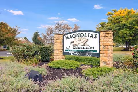 Stone columns frame a Magnolias of Lancaster sign with landscaped planting beds