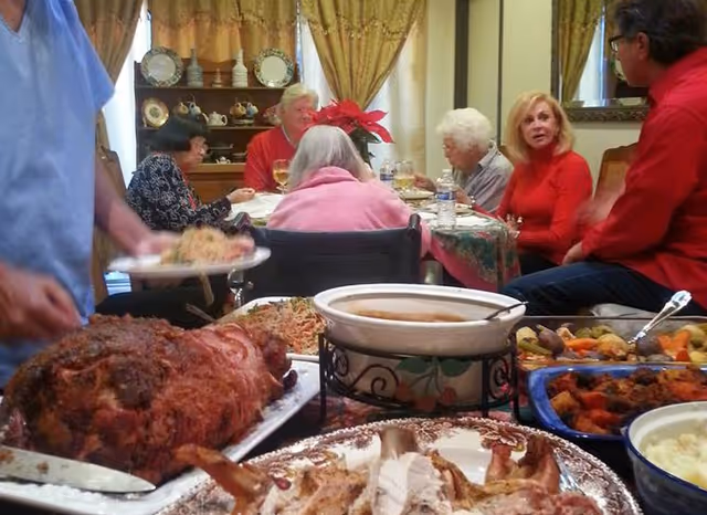 Residents sit around a festive dining table with a variety of dishes.