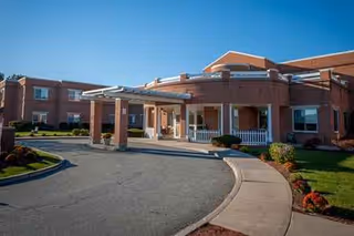 Brick senior living facility exterior with a circular driveway and front entrance.