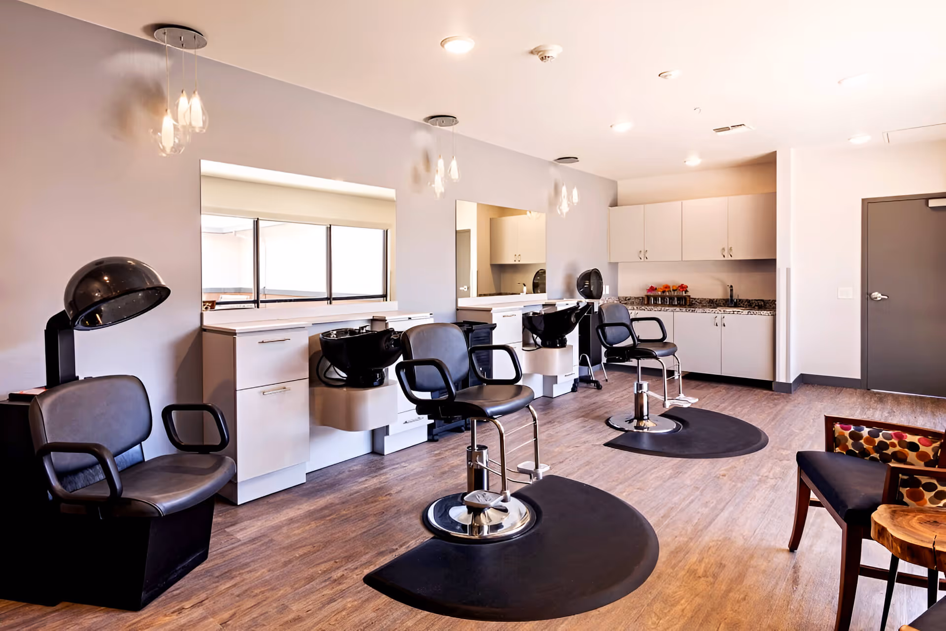 Bright interior salon area with styling chairs, shampoo bowls, mirrors, and cabinetry.