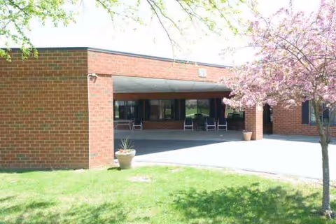 Exterior view of Absolut Care-Three Rivers, brick building with shaded entrance and outdoor seating.