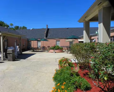 Outdoor courtyard with tables, umbrellas, and planters at Capital Oaks Nursing.