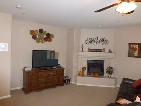 Cozy living room with a TV on a wooden cabinet, fireplace, and a brown sofa.