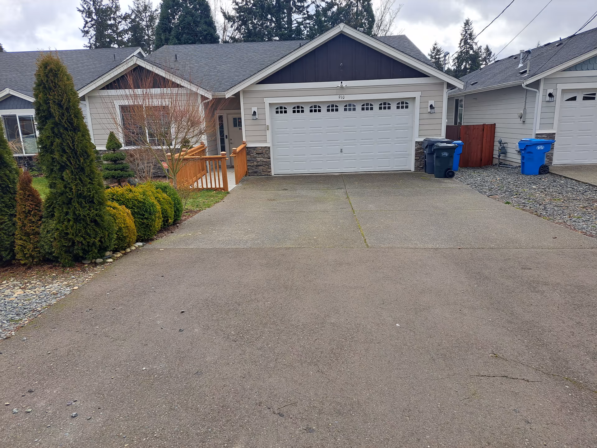 Front view of a single-story house with a double garage, driveway, and landscaped front yard.