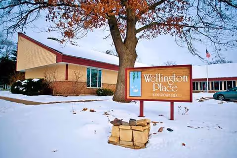 Snowy exterior of Wellington Place at Whiting with front sign and tree.