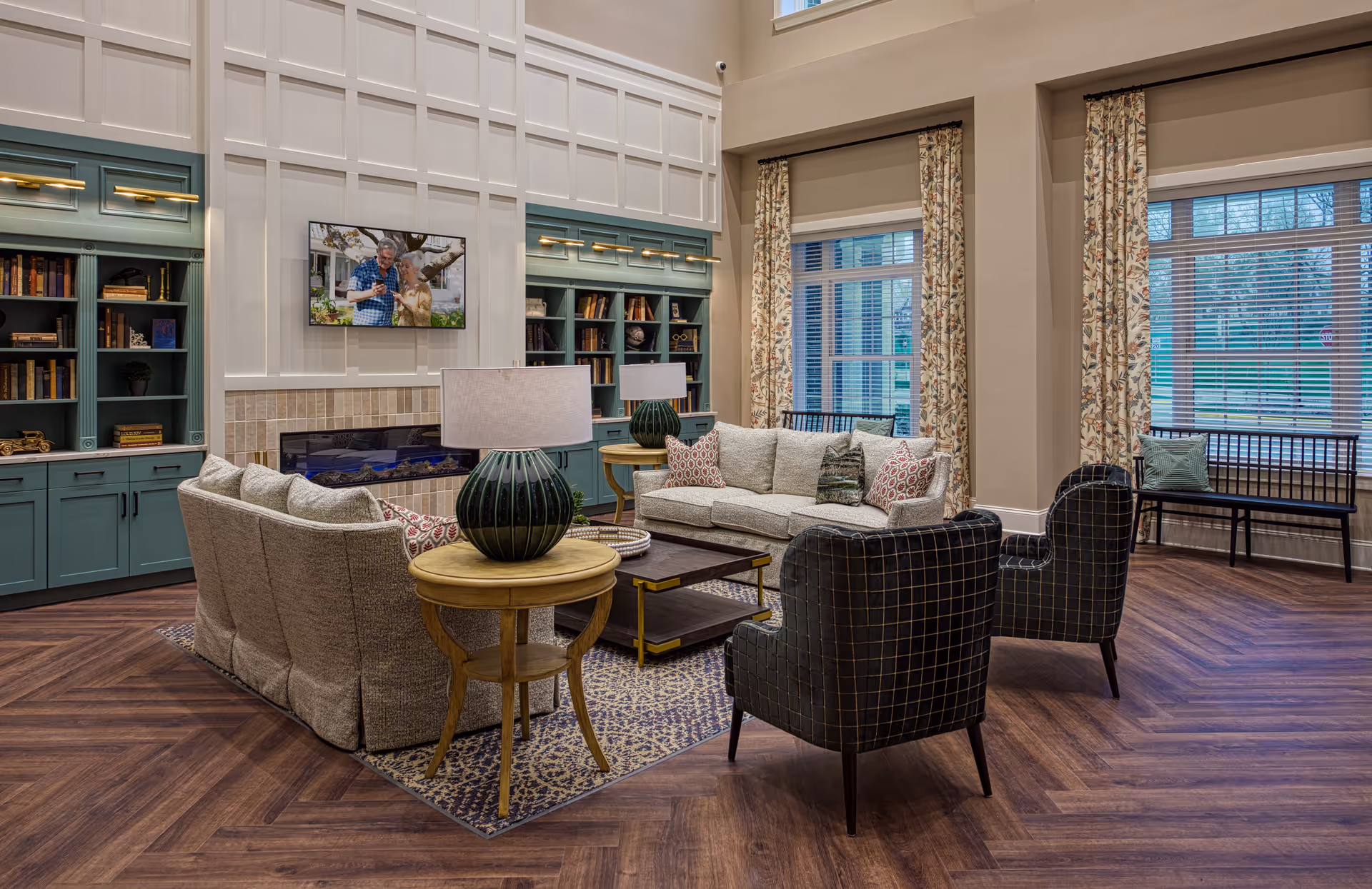 Spacious, well-appointed living room with sofas and armchairs arranged around a coffee table, built-in bookshelves, a fireplace, and large windows.