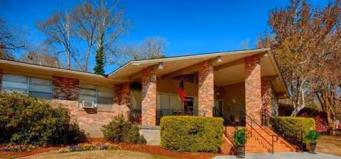 Exterior of a single-story brick facility with a covered entrance and landscaped shrubs.