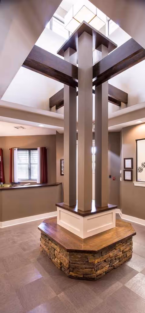 Interior common area with a central multi-pillar sculpture and warm stone base.