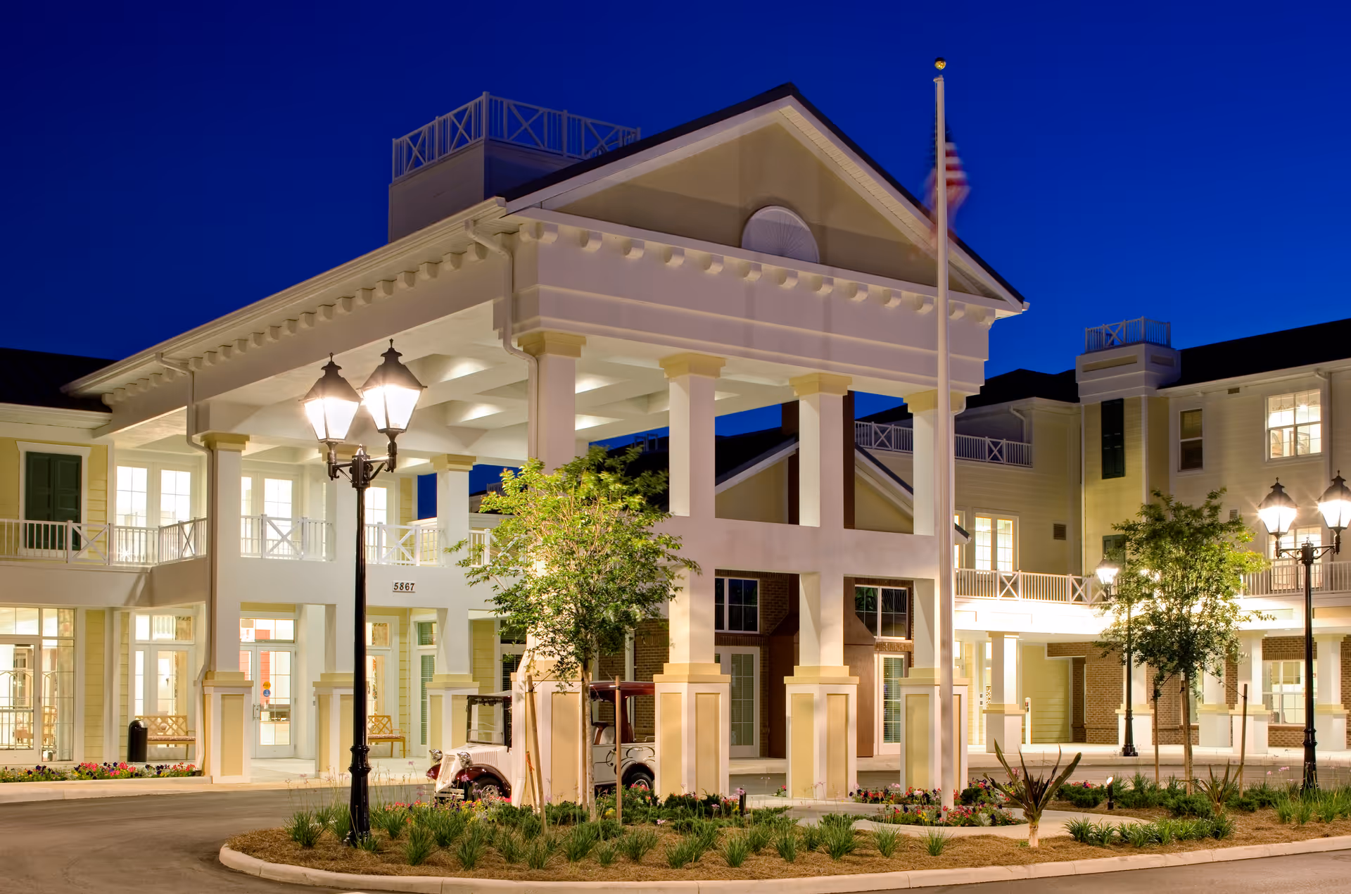 Front entrance of the Watercrest Buena Vista building at dusk with an illuminated portico, lamp posts, and landscaping.