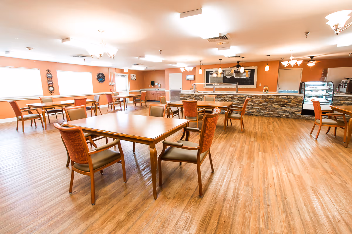 Spacious communal dining room with wooden tables and chairs and a serving counter with a display case.