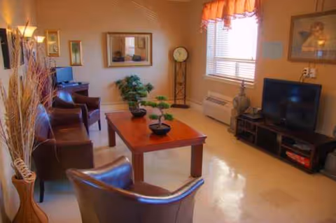 A cozy living room area with chairs, a coffee table, and a TV.