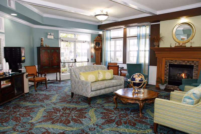 Bright furnished common living room with sofas, a coffee table, a fireplace, and large windows.