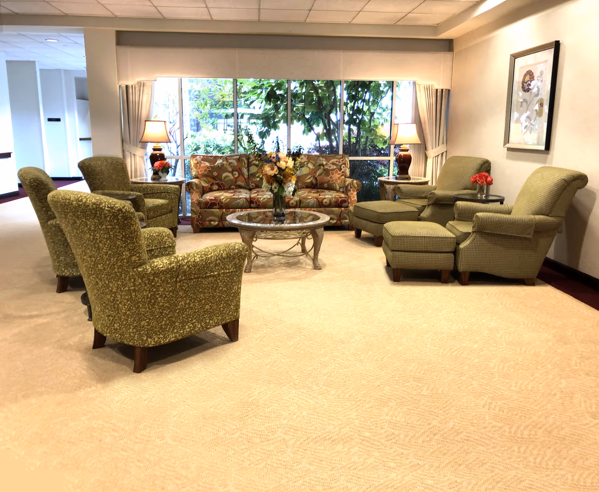 Cozy seating area with floral decor and a coffee table in front of a large window.
