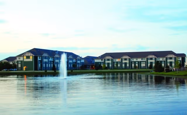 Lakeside view of Timbers of Shorewood with fountain and row of blue buildings.