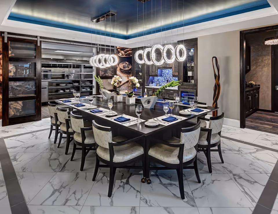 Modern dining room with a large rectangular table set for a meal beneath circular pendant lights.