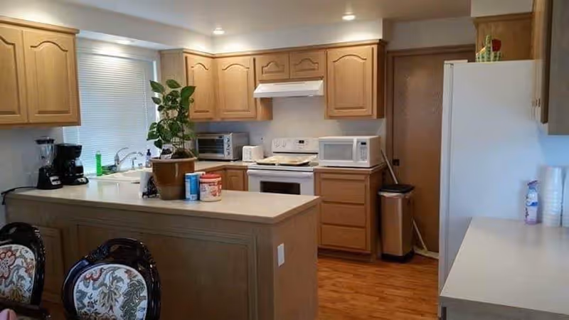 Kitchen with oak cabinets, a central island countertop, stove, microwave, refrigerator, and coffee maker.