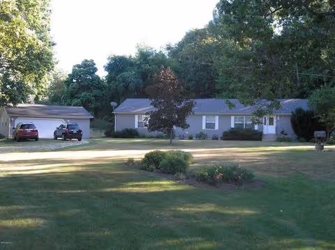Single-story Miracle Adult Foster Care Home exterior with a front yard, driveway, and parked cars.