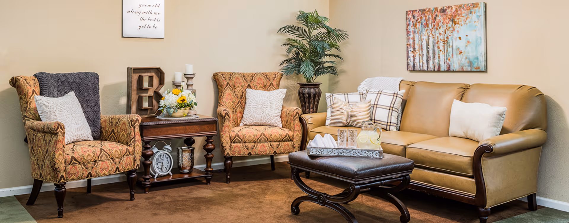 Comfortable sitting area with two patterned armchairs, a leather sofa, an ottoman, side table, and decorative accents.