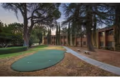 Outdoor courtyard at Sierra Sunrise Apartments features a circular putting green, trees, and a building.