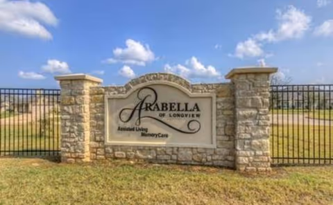 Stone entrance sign for Arabella of Longview Senior Living beside a black metal fence.