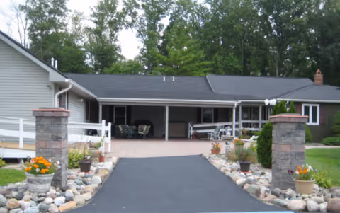 Exterior view of Sandalwood Creek senior living facility with driveway, covered entrance, and landscaping.