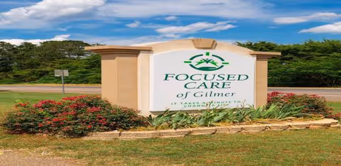 Exterior roadside sign for Focused Care of Gilmer with landscaping and blue sky