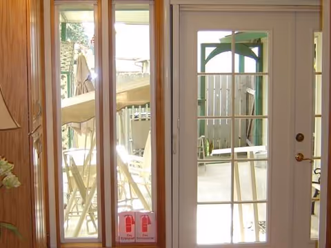 Interior view of glass French doors opening to a sunny patio with outdoor seating
