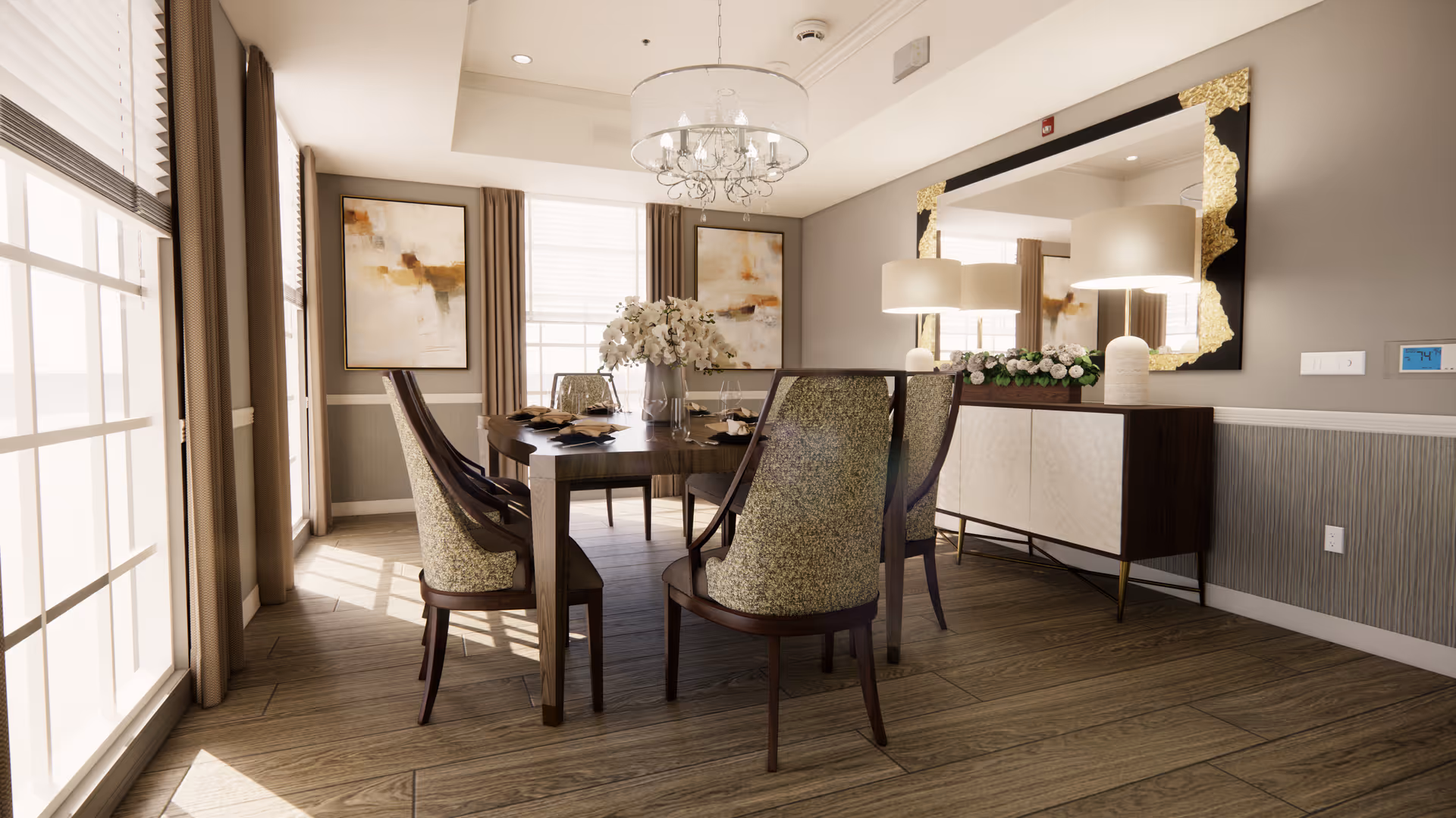 A bright dining room with a wooden table set for six, surrounded by upholstered chairs. The room features large windows with beige curtains allowing natural light to fill the space. On the wall, there are two abstract paintings and a large decorative mirror with gold accents above a sideboard adorned with lamps and floral arrangements. The floor is wooden, and a chandelier hangs from the ceiling.