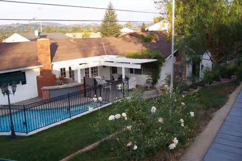 Exterior view of a senior living courtyard with a pool and white building.