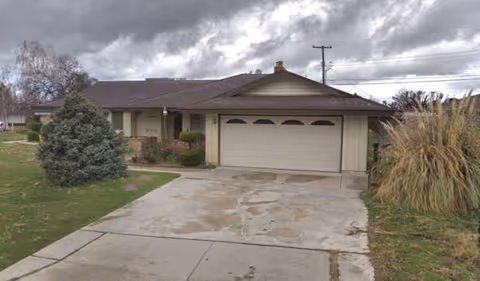 Single-story residential-style building with a two-car garage, driveway, and lawn.