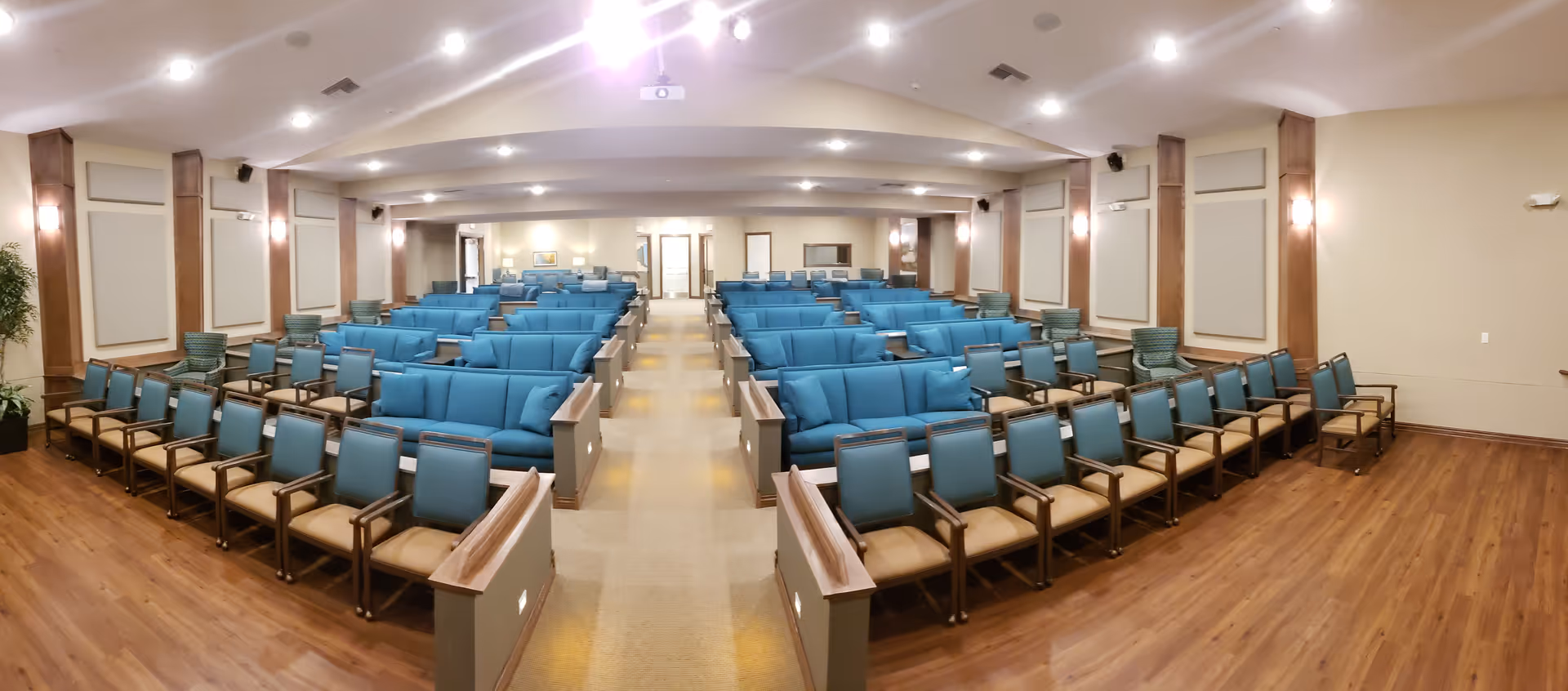 A spacious communal seating area with blue chairs arranged in rows.