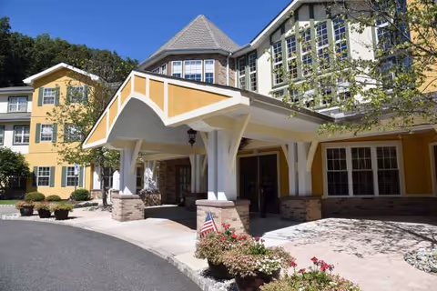 Front entrance of a yellow assisted living facility with a covered entry.