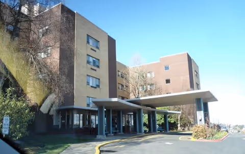 Exterior view of a multi-story senior living building with a covered entrance.