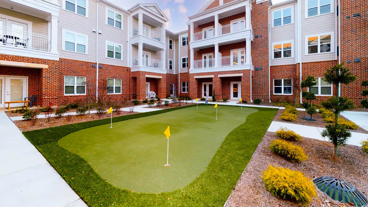 Brick apartment-style courtyard with a small putting green and surrounding landscaping and balconies.