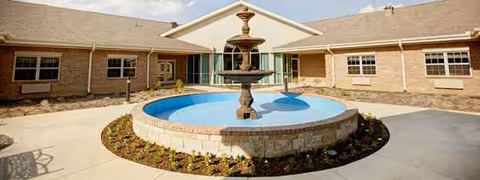 Courtyard with a circular fountain in front of a brick senior living facility.