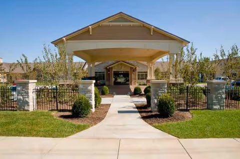 Entrance to a senior living facility with a covered entry and landscaped grounds.