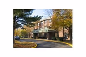 Exterior view of a brick senior living facility with trees and a green awning.