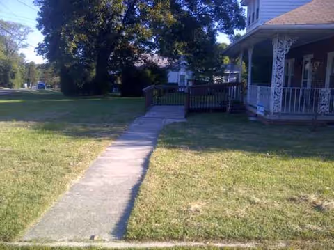 Front exterior of a house-like senior facility with a walkway to a covered porch.