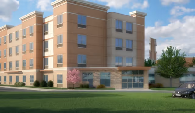 Exterior view of a multi-story senior living building with green lawn and landscaping.