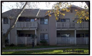 Exterior view of a two-story senior residence with balconies and trees.
