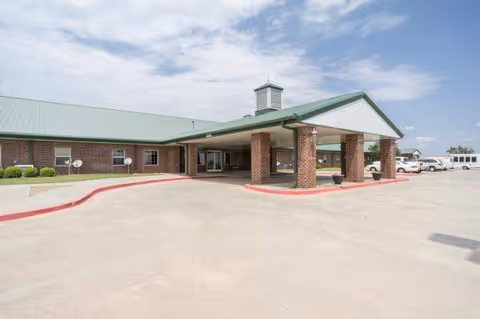 Exterior view of a brick assisted living facility with a green roof and covered entry.