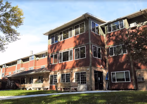 Exterior view of a red-brick Margaret Place senior living building with trees.