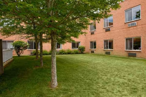 Exterior view of Life Care Center of Plymouth with brick walls, lawn, and trees.