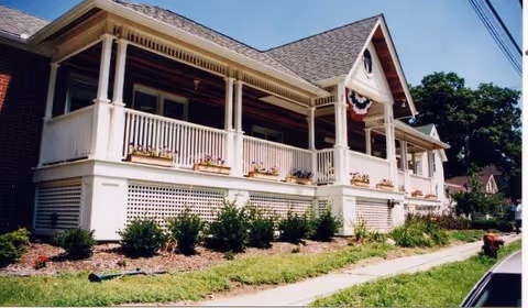 Exterior of Star Manor of Northville, a white front porch with bunting and flower boxes.