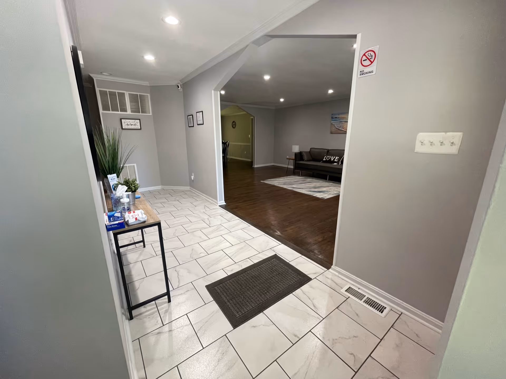 Tiled entrance hallway leading into a living area with a sofa and hardwood floors.