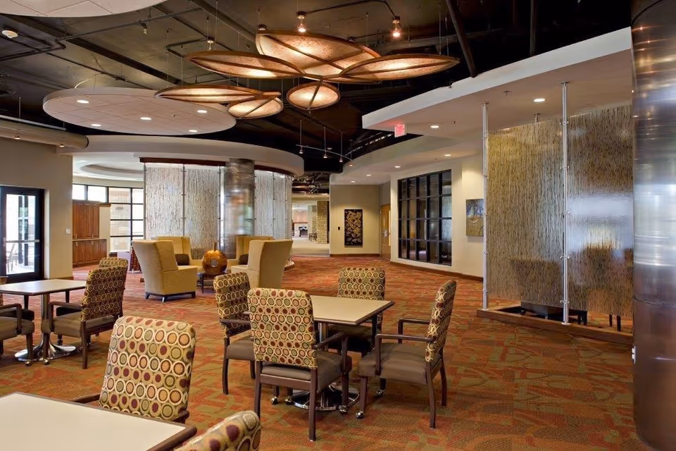 Spacious modern communal dining and lounge area with patterned chairs, tables, and decorative ceiling lights.