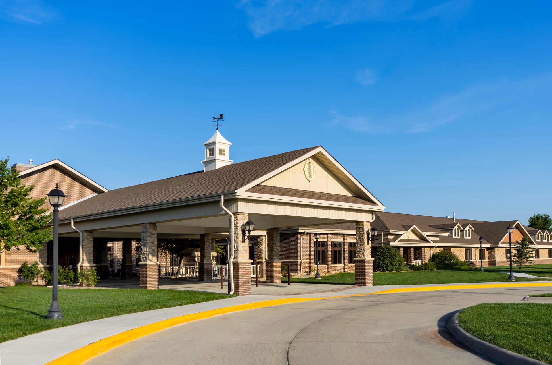 Exterior view of a brick senior living campus with a porte-cochère entrance.