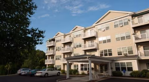 Exterior view of Pillsbury Manor senior living building with balconies and a covered entrance.