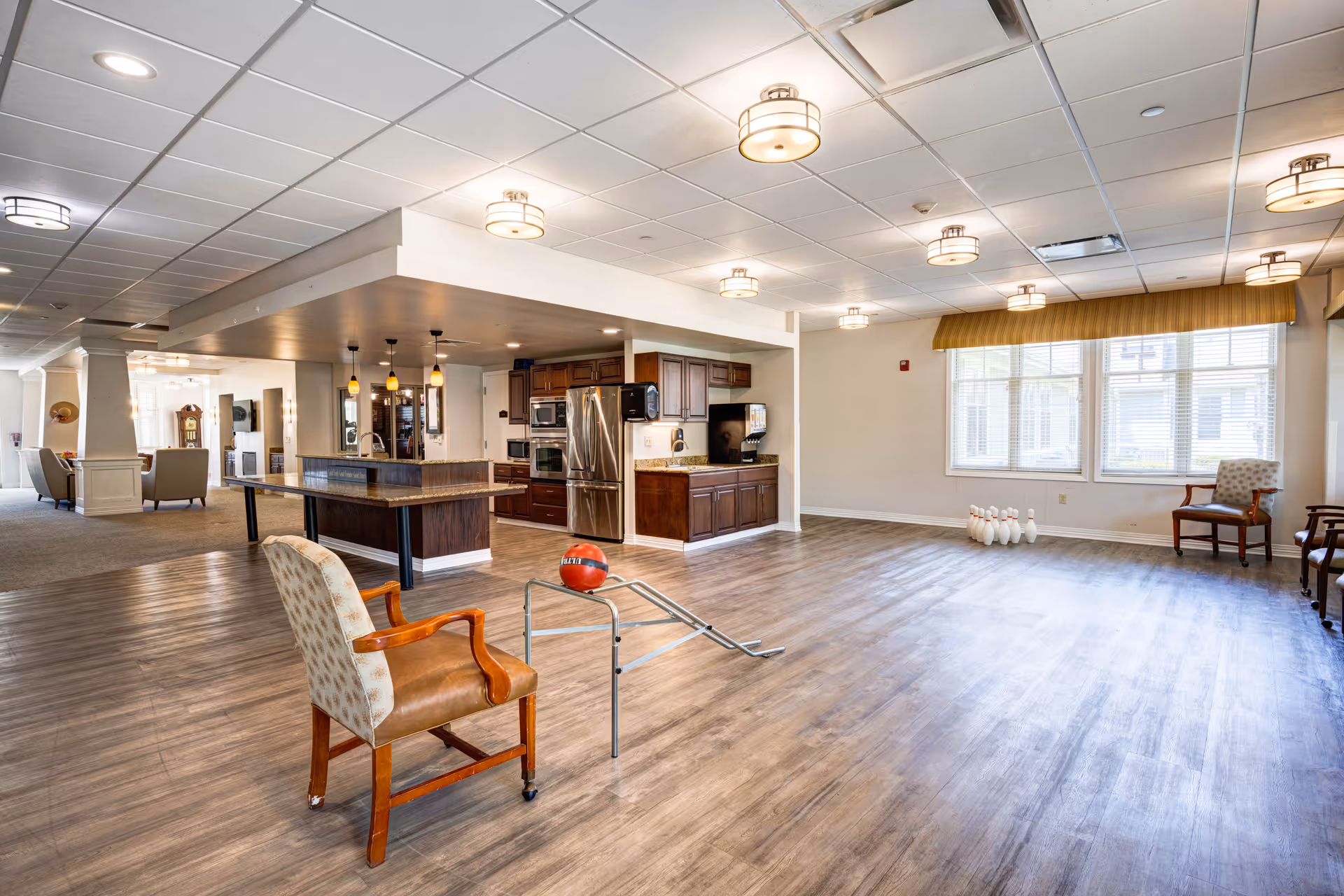 Spacious open interior common area with a kitchen, seating, wood floors, and a small indoor bowling setup.
